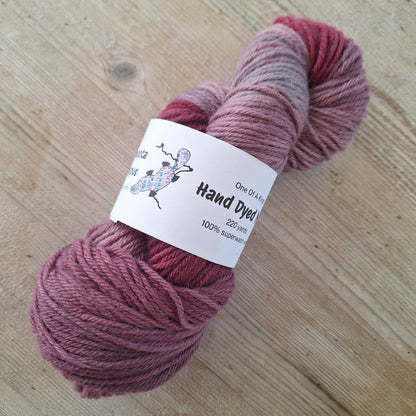 Skein of pink yarn with a label on a wooden surface