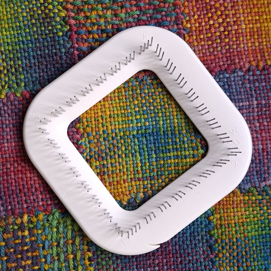 Zoom loom laying on fabric that has been woven on a zoom loom
